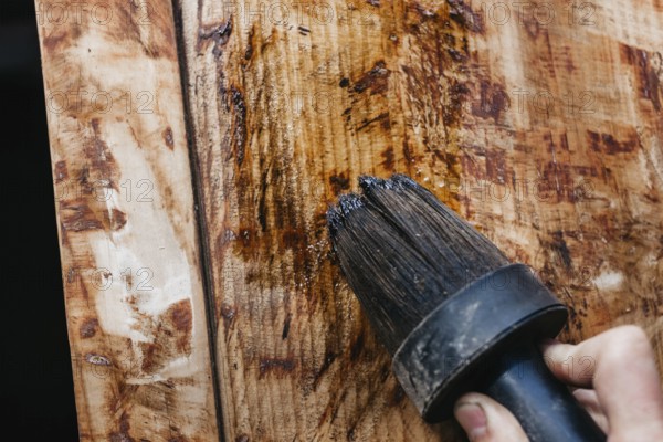 Detailed view of a hand applying varnish to wood, highlighting grain patterns