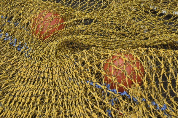 Close-up of a yellow fishing net with red floats and blue rope