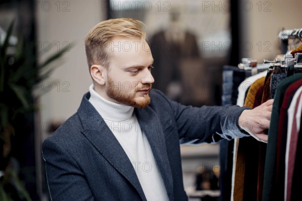 A focused man browses jackets in a clothing store, conveying a sense of style and interest