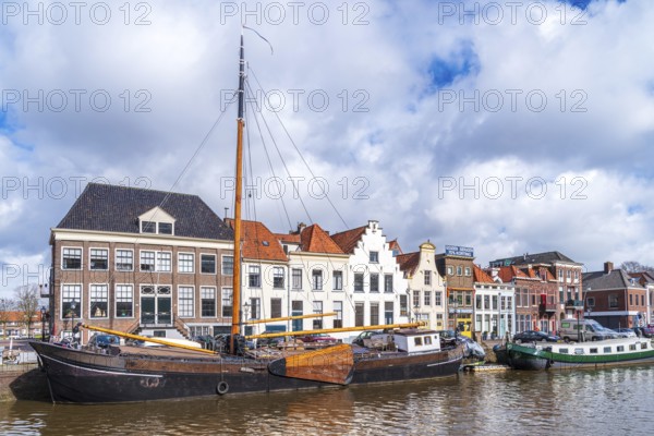 ZWOLLE, NETHERLANDS, MARCH 14, 2021: Old boats and barges in front of some nice gabled houses in the dutch city of Zwolle
