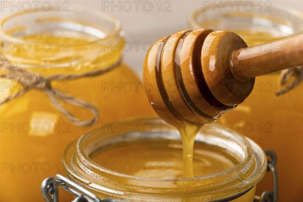 Honey on wooden honey-dipper closeup food background