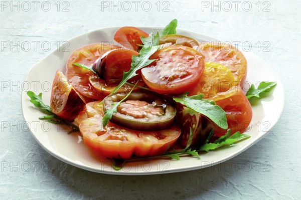 Fresh tomato and rocket salad. A variety of tomatoes of different sorts with arugula leaves. Healthy summer food, Food photography, Food photography