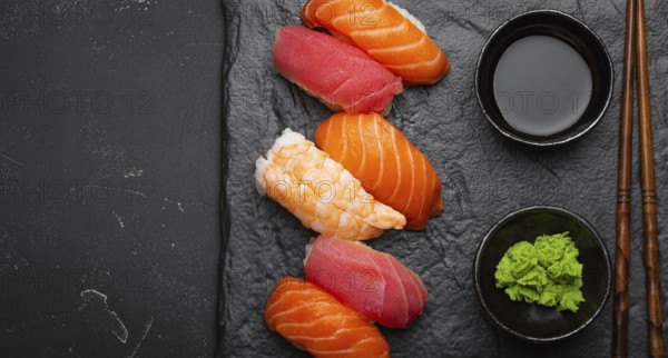 Traditional Japanese sushi with soy sauce, wasabi, chopsticks top view on dark black rustic slate. Sushi with salmon, tuna and shrimp, space for text, food photography, food photography