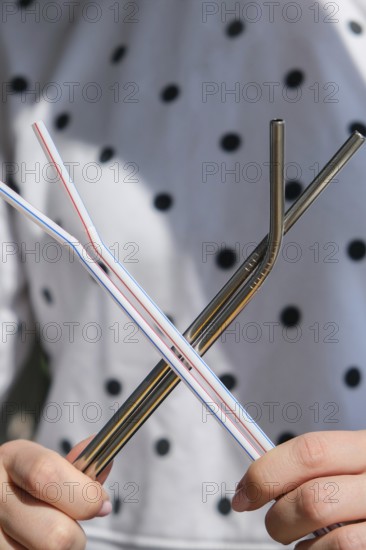 Woman holding Reusable Metal and plastic drinking Straws. Female Hand on reusable collapsible drinking straw. Eco lifestyle and zero waste concept. Plastic free. Stainless metal straws
