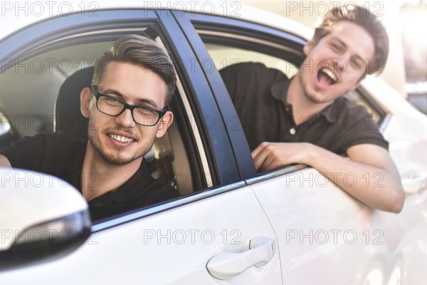 Enjoying travel. Beautiful young couple sitting on the front passenger seats and smiling while handsome man driving a car