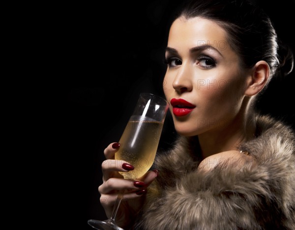 Romantic woman with golden makeup and nailpolish. Big gold fashion necklace. Black isolated background. Holding glass of champagne, Toronto, Canada, North America