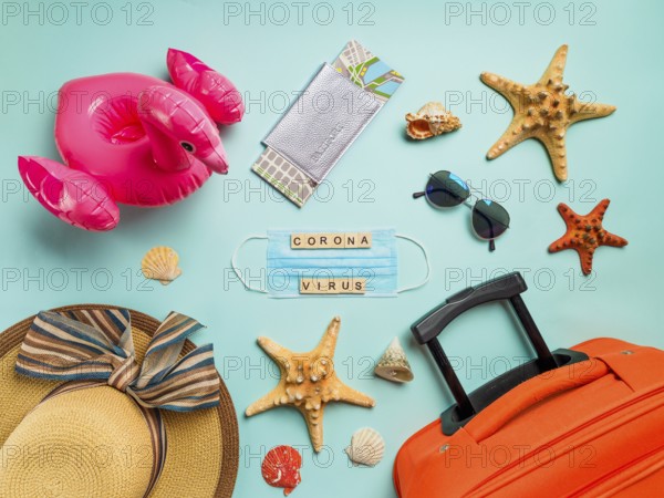 Coronavirus covid-19 and travel concept. Summer vacation and beach rest symbols and breathing mask with wood letters coronavirus on blue background. Flat lay or top view