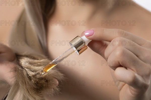 A stylish and fashionable woman carefully applying nourishing hair oil to achieve optimal hydration and shine