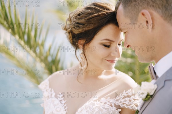 Smiling groom pressed his forehead to bride forehead.