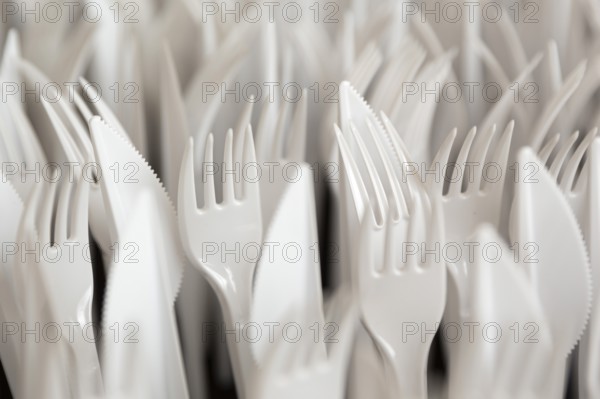 White plastic forks and knifes are seen stacked. Most disposable plastic utensils are made of polystyrene
