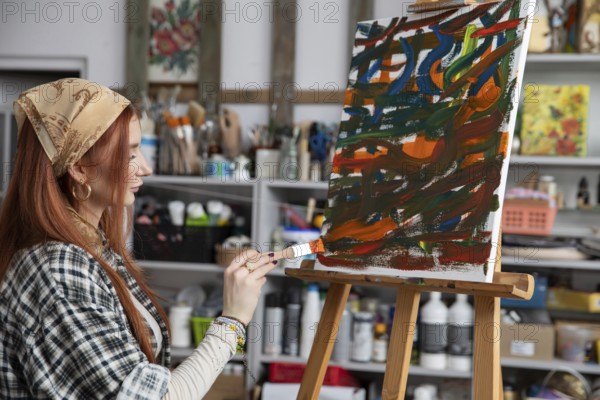 A talented woman artist passionately creates stunning abstract art within her vibrant and colorful studio space