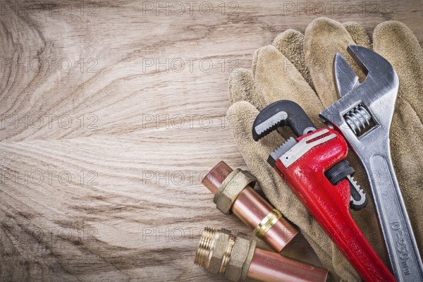 Safety gloves copper water pipe wrench hose nipples adjustable spanner on wooden board plumbing concept