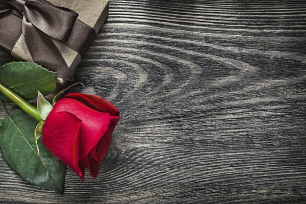 Red rose wrapped present box on wood board copy space holidays concept