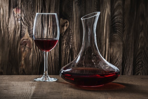 Decanter and glass with red wine on vintage wooden background