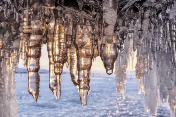 Ice cave on Baikal lake in winter. Blue ice and icicles in grotto in the sunset sunlight. Olkhon island, Baikal, Siberia, Russia, Europe