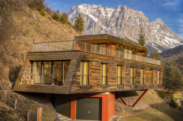 Alpine scenery with a mountain peak in background and in foreground an interesting modern building, a suspended wooden house