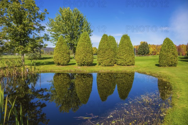 Small quiet pond with water mirror reflecting the blue sky. Phenomenally beautiful park with autumn foliage. Concept Golf tourism