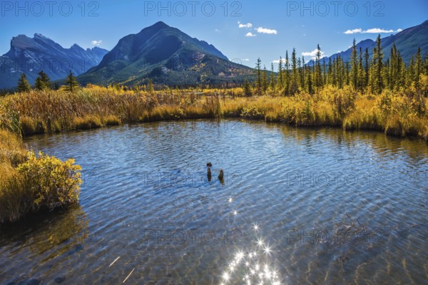 Magic Vermillon lake in the Rocky Mountains of Canada. Solar glare in smooth water. Concept of active tourism and ecotourism