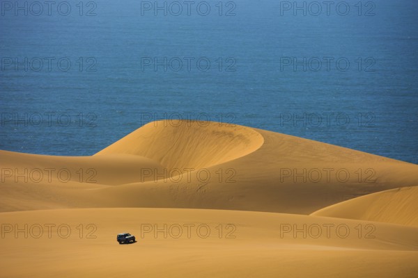 Dangerous and gorgeous jeep - safari through the huge sand dunes on the ocean shore. Atlantic coast of Namibia, south of Africa. The concept of exotic and extreme tours
