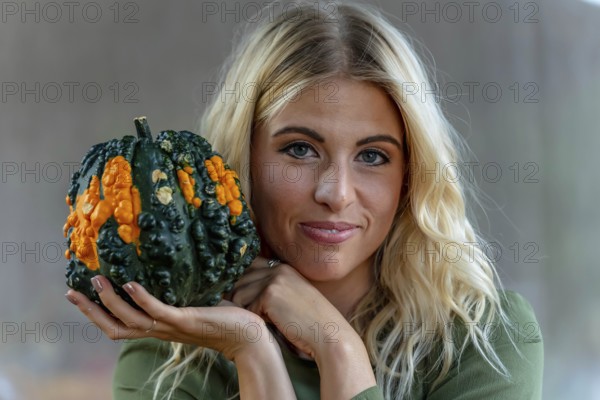A stunning blonde model poses in a vibrant pumpkin field, wearing a stylish autumn outfit with a touch of Halloween charm. The setting glows with warm orange hues and festive seasonal vibes, New Braunfels, United States of America