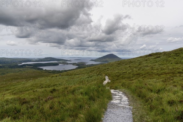 The hiking trail descending from Diamond Hill mountain peak in Connemara National Park with a view of the coast and Kingstown Peninusla