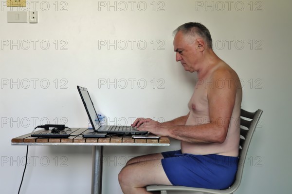 Businessman, freelancer, 60 plus on holiday working with laptop and mobile phone, Pattaya, Chonburi, Thailand, Asia