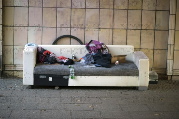 The sleeping place of a homeless person under a bridge with blankets, rubbish and leftover food