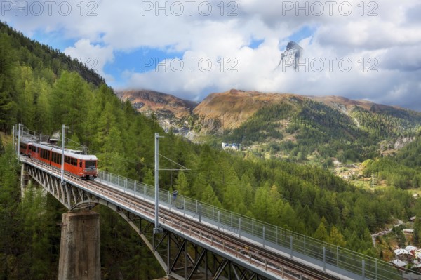 Zermatt, Switzerland. Gornergrat red tourist train on the bridge and Matterhorn peak panorama in Swiss Alps