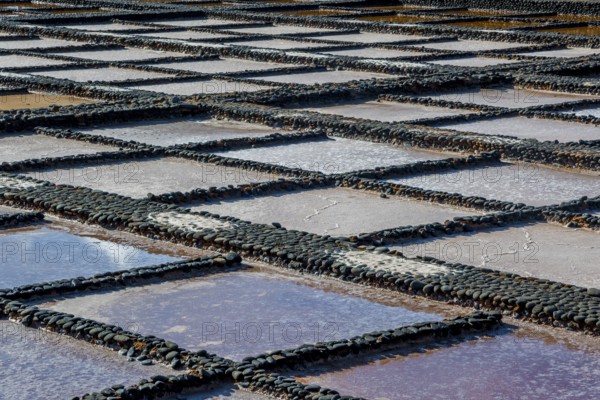 View on traditional rectangular salt evaporation ponds or salt pans creating a grid showing different stages of evaporation and concentration