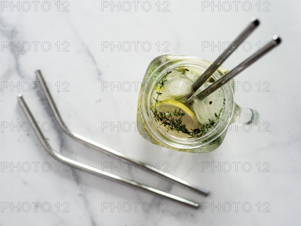 Metal drinking straws and cold drink in glass mason jar on white marble background. Top view or flat lay. Recyclable straws, zero waste concept. Banner