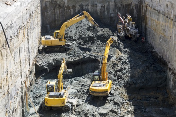 Excavators dig at a construction site of a street and a subway. Baggers transport dirt to a higher level to make room for the subway digging machine. Working fast and efficient