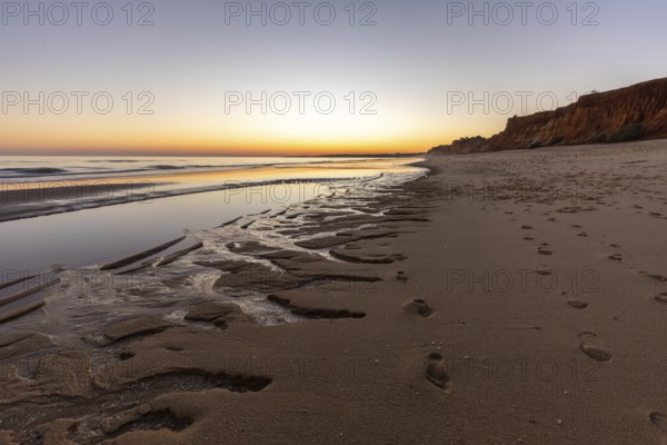 What a sandy beach on the Atlantic. Landscape shot at sunset on a coast with sandstone cliffs. Low tide on the yellow beach of Praia da Falésia near Albufeira, Algarve, Portugal, Europe