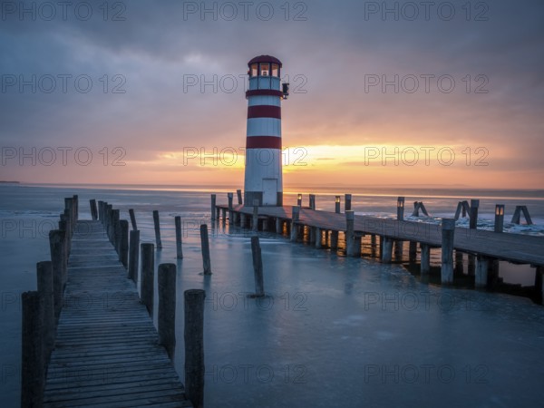 Winter landscape with lighthouse on a lake at sunset