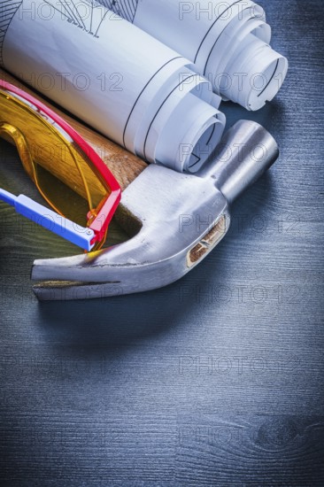 Close up rolled up blueprints hammer goggles