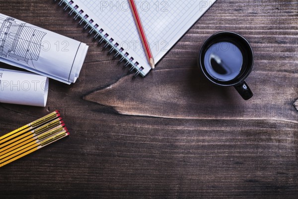 Copybook pencil blueprints wooden meter and cup of coffee on pine wood board construction conceptCopybook pencil blueprints wooden meter and cup of coffee on pine wood board construction concept