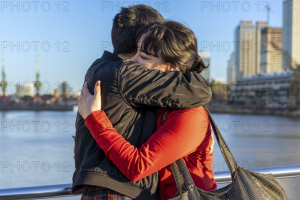 LGBT couple of women embracing each other on a bridge, enjoying a moment of connection