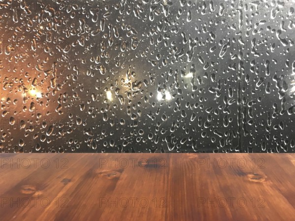 Old brown oak wood table on the blurry drop on window background, wooden table