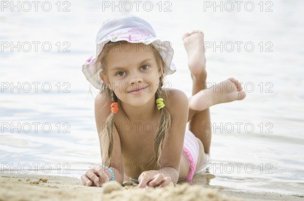 Six year old girl Europeans in panama lying on his stomach on the sand by the river