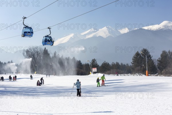 Bansko, Bulgaria, February 11, 2023: Bulgarian winter ski resort panorama with gondola lift cabins, Pirin mountain peaks view and slope, Europe