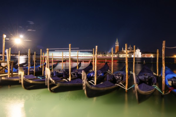Venetian gondolas, boat mooring at St Mark's Square, church of San Giorgio Maggiore in the background, night shot, traces of light, Venice, Veneto, Italy, Europe