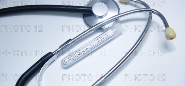 Coronavirus-labeled test tube beside a stethoscope on a white background