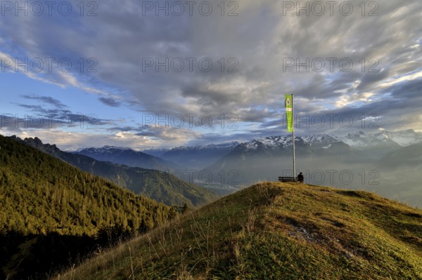 Sitting woman enjoying a dreamlike evening mood in the mountains, view to the Rätikon, flag of the Austrian Alpine Club, Frassenhütte, Vorarlberg, Austria, Europe