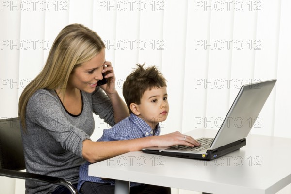Mother and son at the computer, symbol of working from home, family and career, double burden