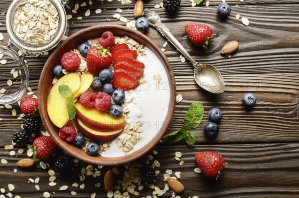 Flat lay of fruit healthy muesli with peaches strawberry almonds and blackberry in clay dish with yogurt