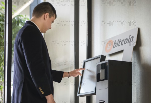 Young businessman buying cryptocurrency on ATM