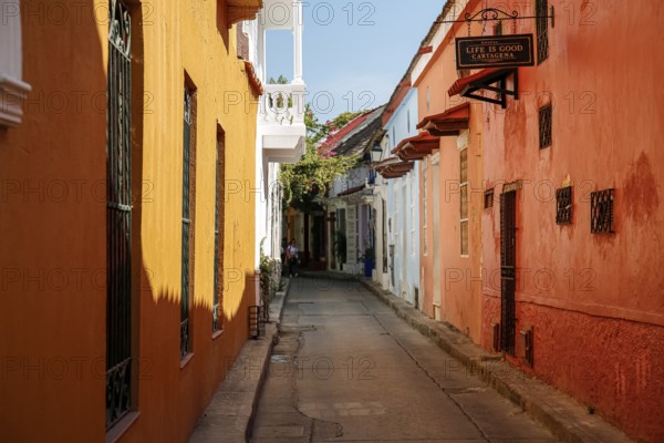 Narrow street in the old town of Cartagena with colorful one-story houses in sunlight and shadow, Colombia, South America