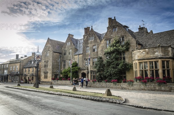 Broadway, UK, August 12, 2015: Main street of Broadway with typical limestone buildings with the traditional architecture in Cotswolds, with tourists walking