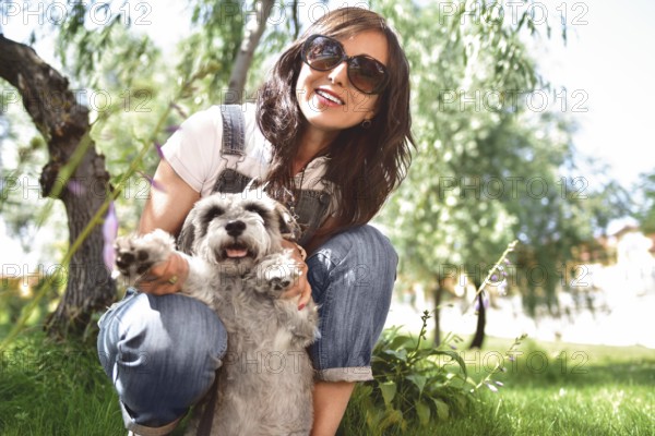 Happy caucasian woman in sunglasses resting in nature with her beloved dog schnauzer