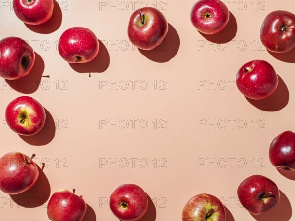Red apples on orange or coral pink background with copy space for text or design in center. Colorful fruit frame. Creative concept. Flat lay or top view, Hard light
