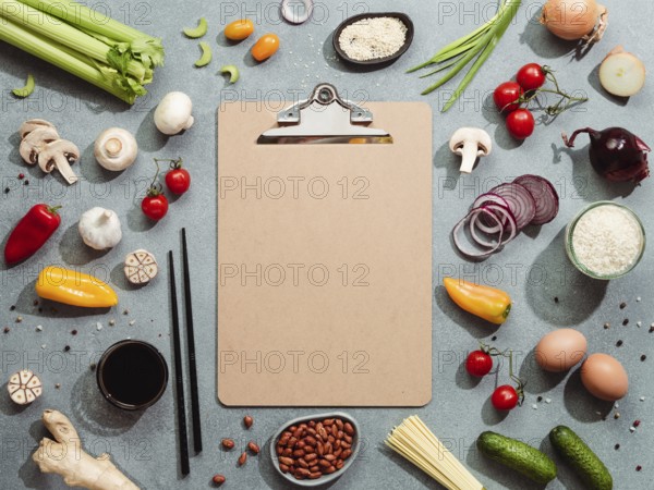 Asian ingredients and empty clipboard. Various of Chinese cooking ingredients and chopsticks on gray stone background. Asian food recipes concept. Copy space for text. Top view or flat lay